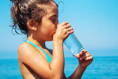 The child drinks water by the sea. Selective focus. Child.の写真素材