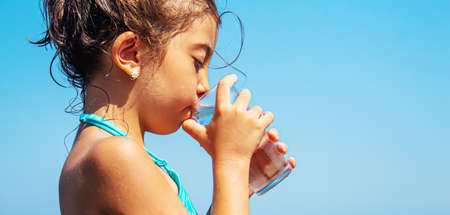 The child drinks water by the sea. Selective focus. Child.の写真素材