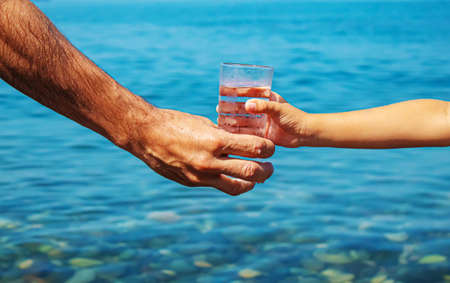 The father gives the child a glass of water. Selective focus.natureの写真素材