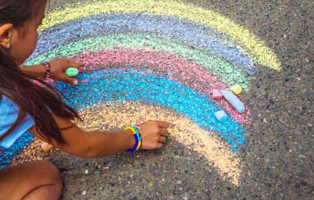 A child draws a rainbow on the asphalt. selective focus. kid.の写真素材