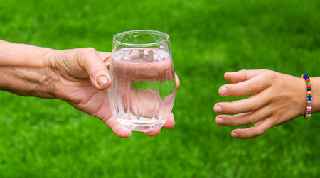 Grandmother giving a glass of clean water to a child. Selective focus. nature.の写真素材