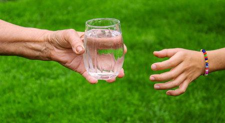 Grandmother giving a glass of clean water to a child. Selective focus. nature.
