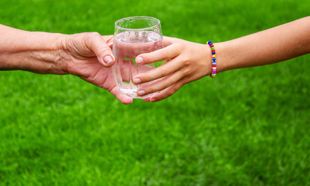 Grandmother giving a glass of clean water to a child. Selective focus. nature.の写真素材