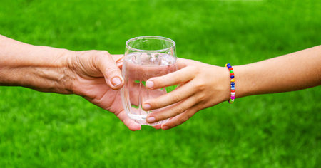 Grandmother giving a glass of clean water to a child. Selective focus. nature.の写真素材