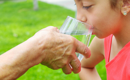 Grandmother giving a glass of clean water to a child. Selective focus. nature.の写真素材