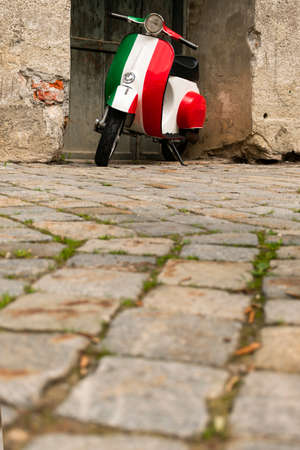 30 May 2019, Tuscany, Italy - Vintage motorbike in italian flag colors parked near old rustic wall.のeditorial素材