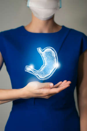 Woman in blue clothes holding virtual Stomach in hand. Handrawn human organ, detox and healthcare, healthcare hospital service concept stock photoの写真素材