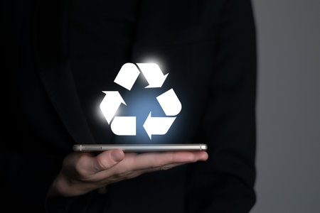 Hand holding recycle symbol on a screen of mobile phone. Mobile applications as asource of information about recycle and sustainability.の写真素材