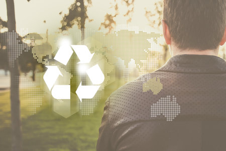 Man from back looking to the sunrise, recycle symbol wit planet continents silhouette on bokeh background. Clean future and recycle concept.の写真素材