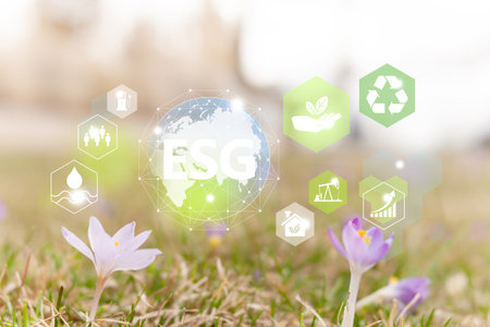 ESG investment strategy concept. Ecology icons with ESG sign and planet Earth illustration. Small flowers on the ground in park background.の写真素材