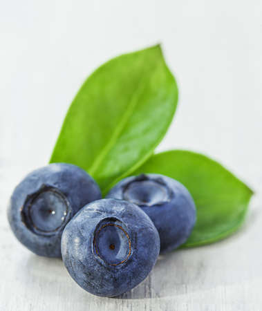 a fresh crop of blueberries lies on a white wooden tableの写真素材