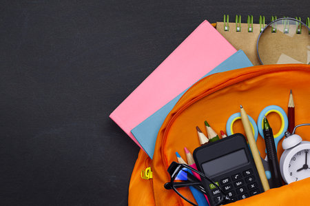 satchel with school supplies on the background of a blackboardの写真素材