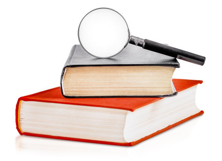 two hardcover books with a magnifying glass are highlighted on a white backgroundの写真素材