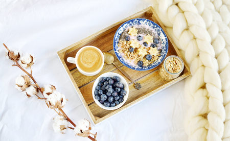 Fresh Breakfast Yogurt with Muesli Banana Berries Chia Seeds Granola Cotton Flower White Giant Knit Blanket Bedroom Healthy Lifestyleの写真素材