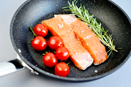 Salmon Trout Fillet on Pan Cooking Raw Fish Pepper Salt Rosemary Tomato Cherry Lemon Lifestyle Healthy Conceptの写真素材