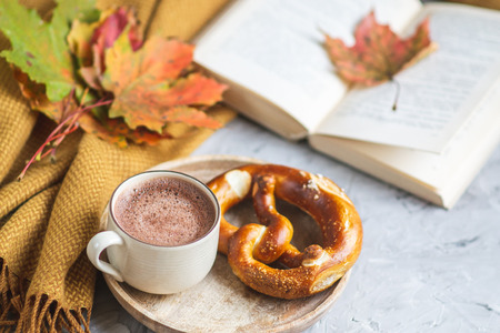 Tea Cup Hot Chocolate Coffee Autumn Time Bakery Pretzel Toned Photo Knitting Scarf Blanket Yellow Leaves Gray Backgroundの写真素材