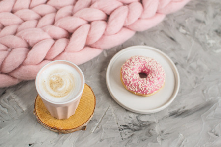 Cup with cappuccino, doughnut, pink pastel giant blanket, flowers, bedroom, morning conceptの写真素材