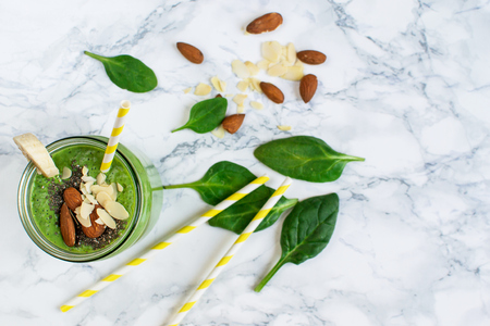 Green spinach smoothies in jar with seeds, almonds nuts, healthy food conceptの写真素材