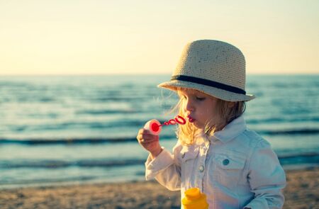 Riga, Latvia - June 28 2018: Little girl blowing bubbles at the sea. Toned photoのeditorial素材