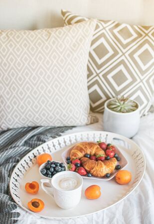Morning breakfast in bed, cup of coffee, croissants, fresh berries, pot with succulent. Healthy food concept. Scandinavian styleの写真素材