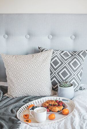 Morning breakfast in bed, cup of coffee, croissants, fresh berries, pot with succulent. Healthy food concept. Scandinavian styleの写真素材