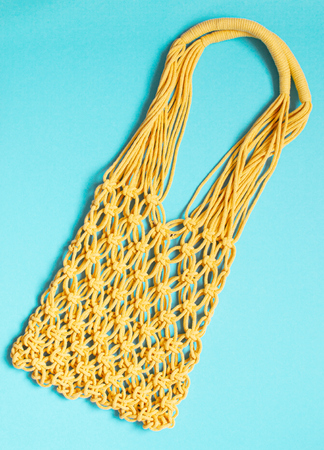Handmade yellow macrame bag on the blue background, ECO friendly. Modern summer beach conceptの写真素材