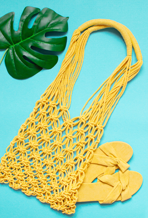 Handmade yellow macrame bag on the blue background, ECO friendly. Modern summer beach conceptの写真素材