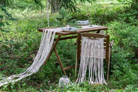 Wedding reception table with macrame tablecloth, decoration on a rustic wooden tableの写真素材