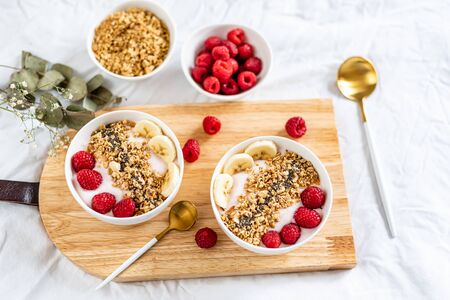 Yogurt with granola, chia seed, raspberry and banana, healthy breakfast concept, top viewの写真素材
