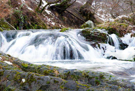 River waterfall and frozen water, rocks on foregroundの写真素材