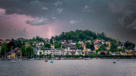 Thunderstorm coming over a city on the lake, city view and boats in the lake waiting for the coming stormの写真素材