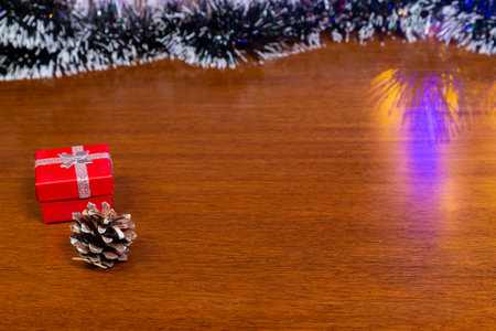 Red, yellow and silver Christmas present. On top of wooden table with background of Christmas trees.の写真素材