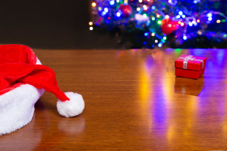 Red, yellow and silver Christmas present. On top of wooden table with background of Christmas trees.の写真素材