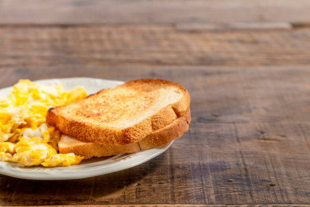 Plate with toast and eggs, on a rustic wooden table. Horizontal photo with space for textの写真素材
