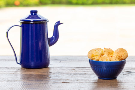 Pestic Brazilian, Cheese Bread. On a rustic table. And the bottom is a blue coffee pot.の写真素材