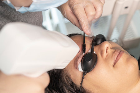 Cosmetologist making permanent makeup on the eyebrows of a young womanの写真素材