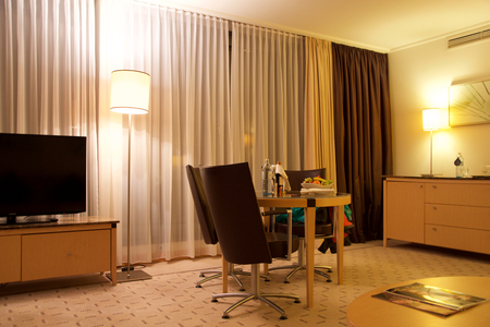 VIENNA, AUSTRIA - APR 28th, 2017: Romantic evening with bottle of red wine, sweets and fruits in the luxury hotel room on a table with three leather chairs, Hilton Penthouse Suiteのeditorial素材