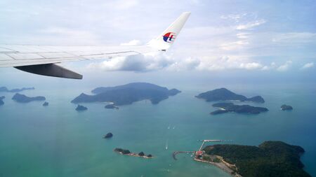 KEDAH, LANGKAWI, MALAYSIA - APR 11th, 2015: Scenery from airplane window seeing wing of airplane, white clouds, blue sky and beautiful islandsのeditorial素材