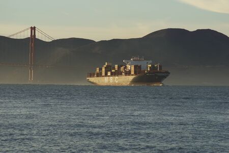 SAN FRANCISCO, CALIFORNIA, UNITED STATES - NOV 25th, 2018: MSC Cargo Ship SILVIA entering the San Francisco Bay under the Golden Gate Bridge on its way to the Port of Oakland - a fully loaded container ship during sunsetのeditorial素材