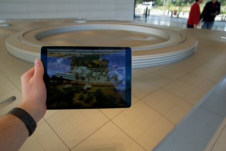 CUPERTINO, CALIFORNIA, UNITED STATES - NOV 26th, 2018: People at the Apple Park Visitor Center in Silicon Valley explore the new Apple Offices using a scaled-down replica of the campus and a virtual reality programのeditorial素材