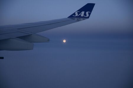 COPENHAGEN, DENMARK - NOV 24th, 2018: View of the moon and the wing from window of a flying plane, wingview of an airplaneのeditorial素材