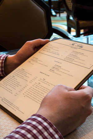CHICAGO, ILLINOIS, UNITED STATES - DEC 11th, 2015: Close up of man finger with menu choosing dishes at restaurantのeditorial素材