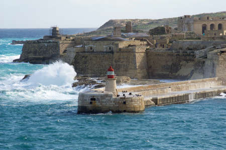 VALLETTA, MALTA - DEC 31st, 2019: View from Fort St Elmo on to the Ricasoli Grand Harbour East Breakwater and red lighthouse during strong wavesのeditorial素材