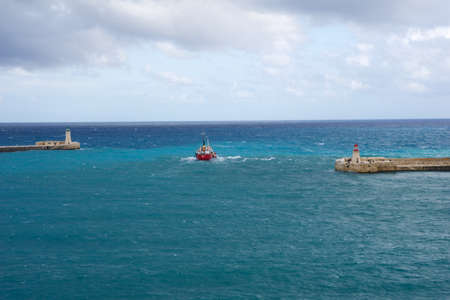 VALLETTA, MALTA - DEC 31st, 2019: View from Fort St Elmo on Red and Green Lighthouse pier light at the harbour entrance of grand Harbour Valletta Malta with red shipのeditorial素材