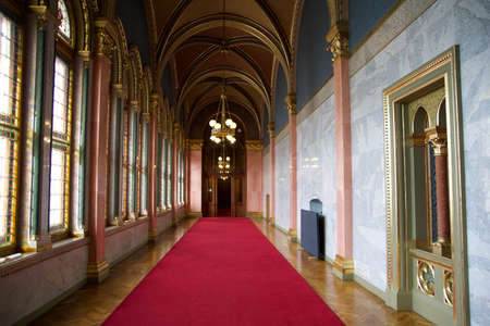 BUDAPEST, HUNGARY - 03 MAR 2019: Long hallway with red carpet on marble floor and chandelier on the ceiling in the Hungarian Parliament buildingのeditorial素材