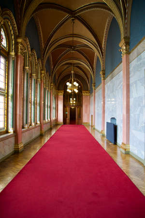 BUDAPEST, HUNGARY - 03 MAR 2019: Long hallway with red carpet on marble floor and chandelier on the ceiling in the Hungarian Parliament buildingのeditorial素材