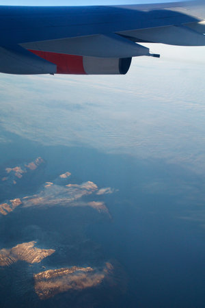 COPENHAGEN, DENMARK - 24 NOV 2018: Aeroplane window view with plane wing flying over the icebergs of Greenland at sunset with aerial perspectiveのeditorial素材