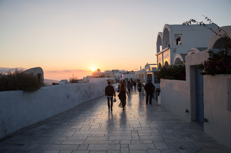 People Walking towards a Sunset with Sea View in Oia, Santorini, Cyclades, Greeceの写真素材