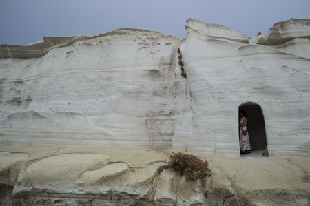 Woman Standing in Cave at Sarakiniko Beach in Milos, Cyclades, Greeceの写真素材