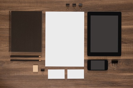 Branding mockup set on brown wooden desk. Blank business cards with mobile and tablet. White document.の写真素材
